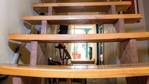 A wooden staircase with a chair at the bottom. - by cao rest house (Bogotá)