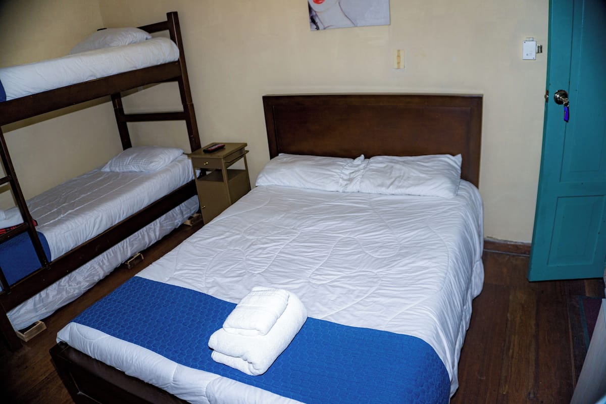 A bunk bed room with a single bed, a nightstand, and a teal door.