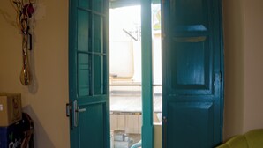 A room with a wooden floor, a teal door, and a green chair. - by cao rest house (Bogotá)