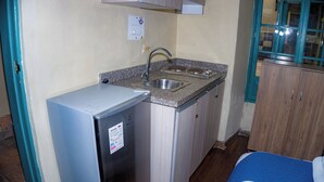A compact kitchen with a refrigerator, sink, and wooden cabinets. - by cao rest house (Bogotá)