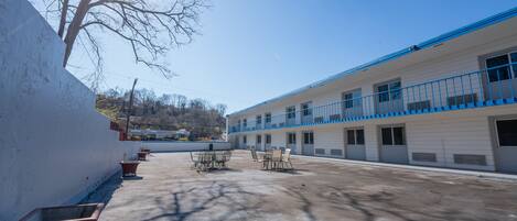 A motel with a courtyard, outdoor seating, and a view of the surrounding area.