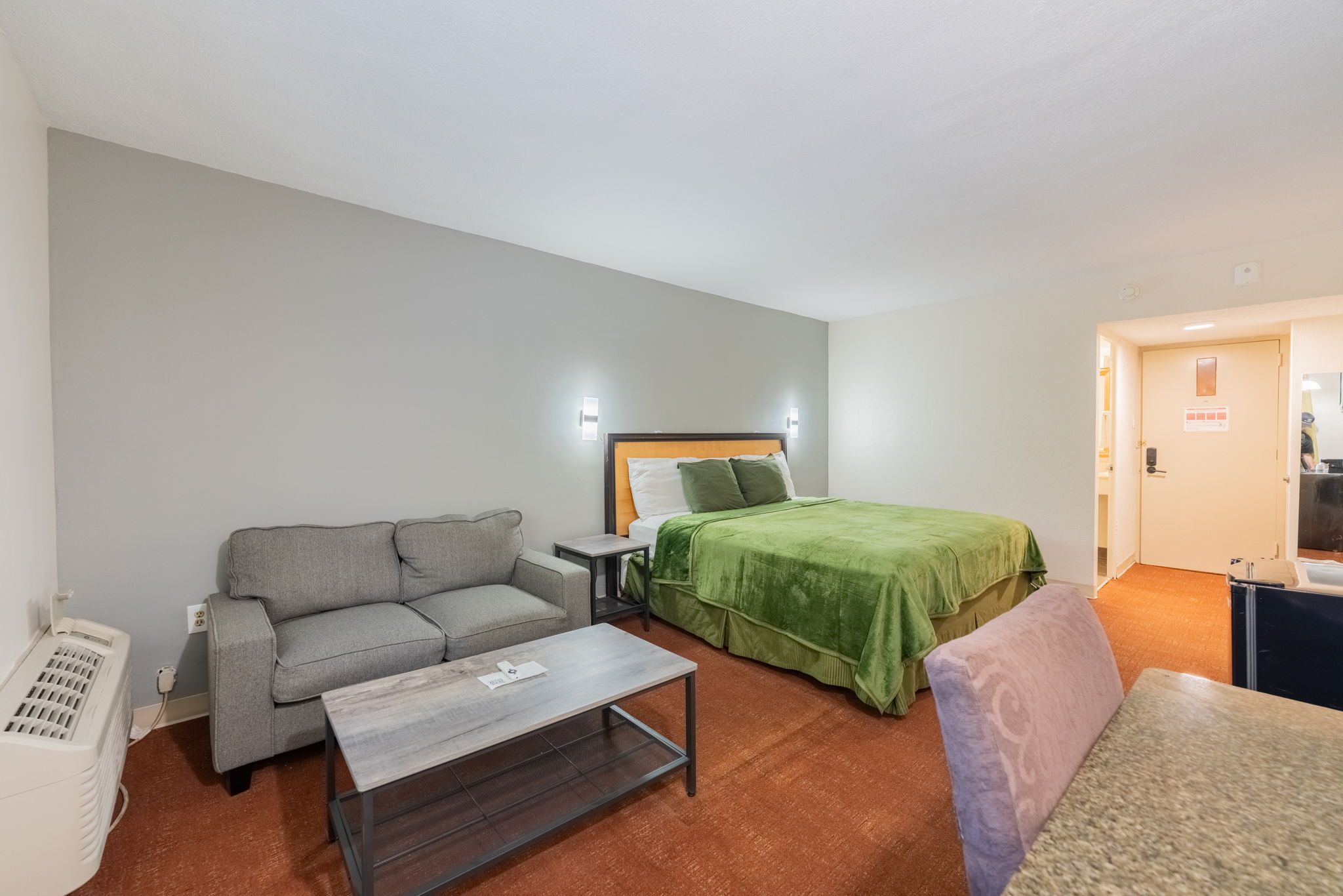 Une chambre d’hôtel avec un lit, un canapé, une petite table et un radiateur.