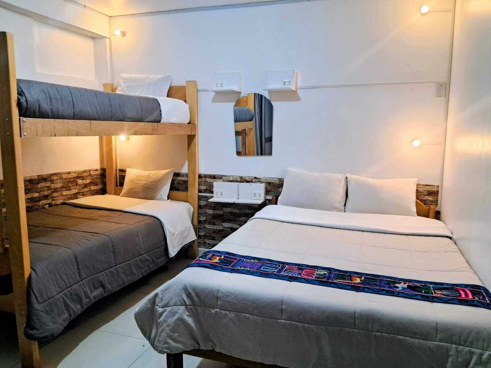 Una habitación con literas, una cama grande y una mesita pequeña.