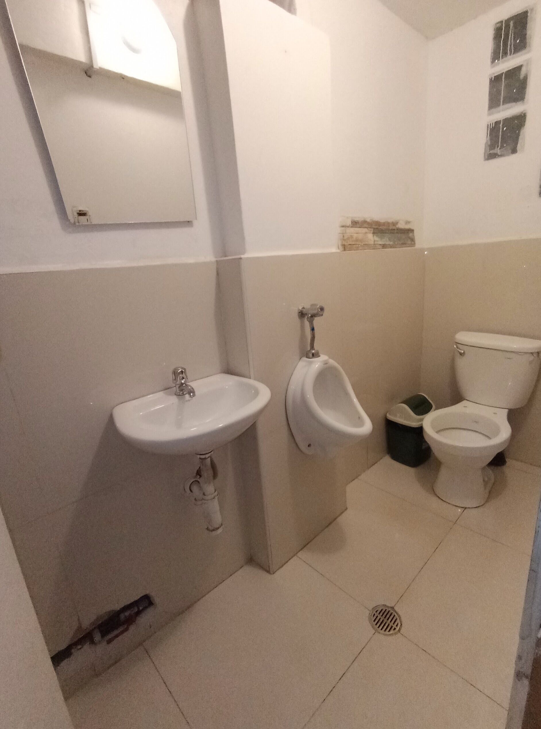 Een kleine, schone badkamer met een wastafel, urinoir en toilet.
