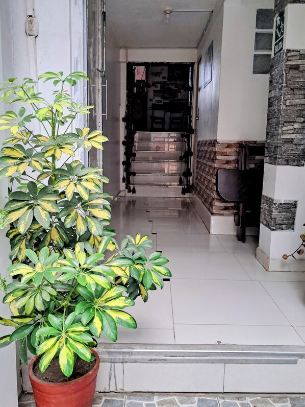 A hallway with a potted plant, a tiled floor, and a door leading to another room. - HOSTAL LA RASA (Cusco)