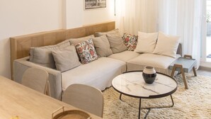 Ein modernes Wohnzimmer mit einem Ecksofa, einem runden Couchtisch und einer außergewöhnlichen Deckenleuchte.