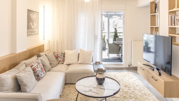 Ein modernes Wohnzimmer mit Sofa, Couchtisch und Fernseher.