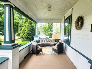 Een overdekt terras met een hoekbank en een decoratieve krans aan de muur.