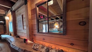 A cozy cabin interior with a wooden wall, a window with a mirror, a pool table, and a sign that reads "Life is better on the slopes." - Experience Bethel charm near Sunday River  (Bethel)
