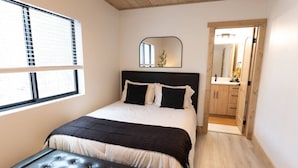 Une chambre à coucher avec un lit, une table de chevet, un miroir et un plancher en bois.