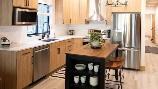 Une cuisine moderne avec des meubles en bois, des appareils en acier inoxydable et un îlot central doté de tabourets.