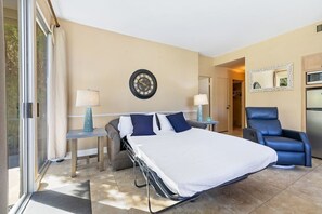 A hotel room with a bed, two bedside tables, a chair, a clock, a mirror, and a door leading to a closet.