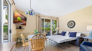 A room with a dining table, chairs, a sofa, a TV, and a bed. - Condo paradise in Indian Wells. (Indian Wells)
