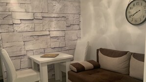 Una sala de estar moderna con una pared de piedra, una mesa blanca, un sofá marrón y un sillón blanco.