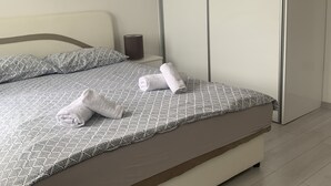 Una cama bien hecha con una colcha estampada, dos espejos decorativos en la pared y un armario cerrado.