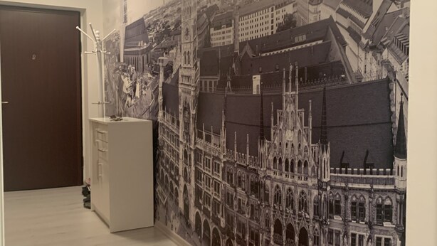 Una habitación con un gran mural blanco y negro de un paisaje urbano, un armario blanco y una puerta.