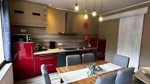 Una cucina moderna con mobili rossi, un tavolo da pranzo in legno e un forno integrato.