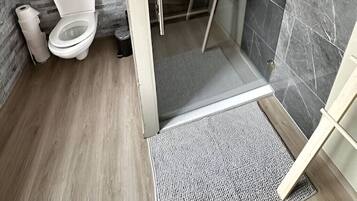 Un baño con inodoro, ducha y pared de mármol.