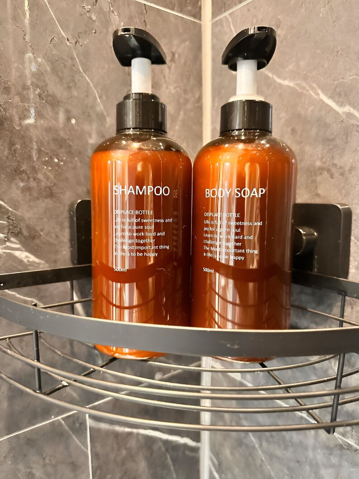 Two bottles of shampoo and body soap in a metal rack.