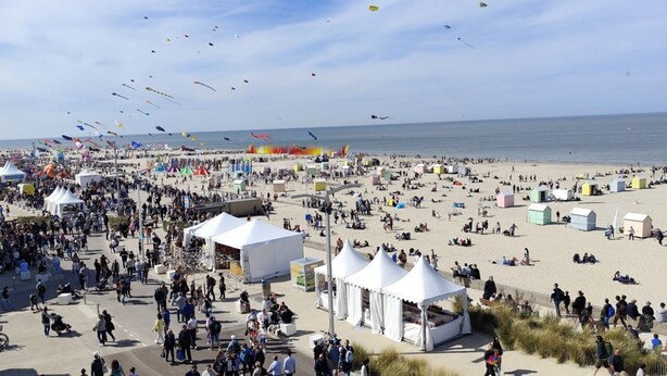 Een druk strand met tenten en mensen.