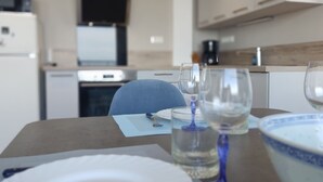 Een eettafel gedekt met een bord, een glas en een kom, met een keuken op de achtergrond.
