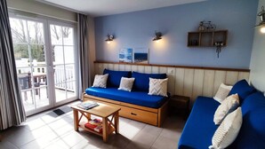 A living room with a blue sofa, a wooden coffee table, and a sliding glass door leading to an outdoor area.