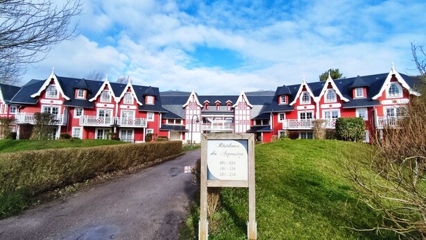 En stor, röd och vit byggnad med många fönster och en skylt framför.
