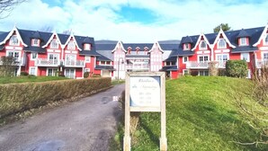 A large red building with multiple balconies and a signboard in front. - Appartement Belle Dune 1 Chambre (Fort-Mahon Plage)