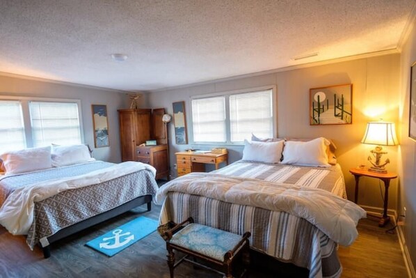 A hotel room with two beds, a desk, a chair, and a window with blinds. - Charming Waterfront Cottage – Private Dock, Panoramic Views, and park passes! (Murrells Inlet)