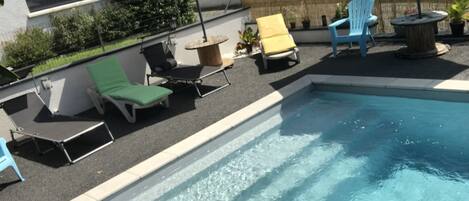 Una piscina con sillones de descanso y sombrillas.