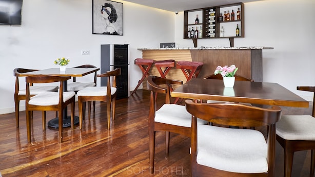 A modern dining area with wooden tables and chairs, a bar with a wine rack, and a painting on the wall. - SOFT HOTEL (Douala)