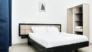 A modern bedroom with a bed, a wooden wardrobe, and a framed picture on the wall. - SOFT HOTEL (Douala)