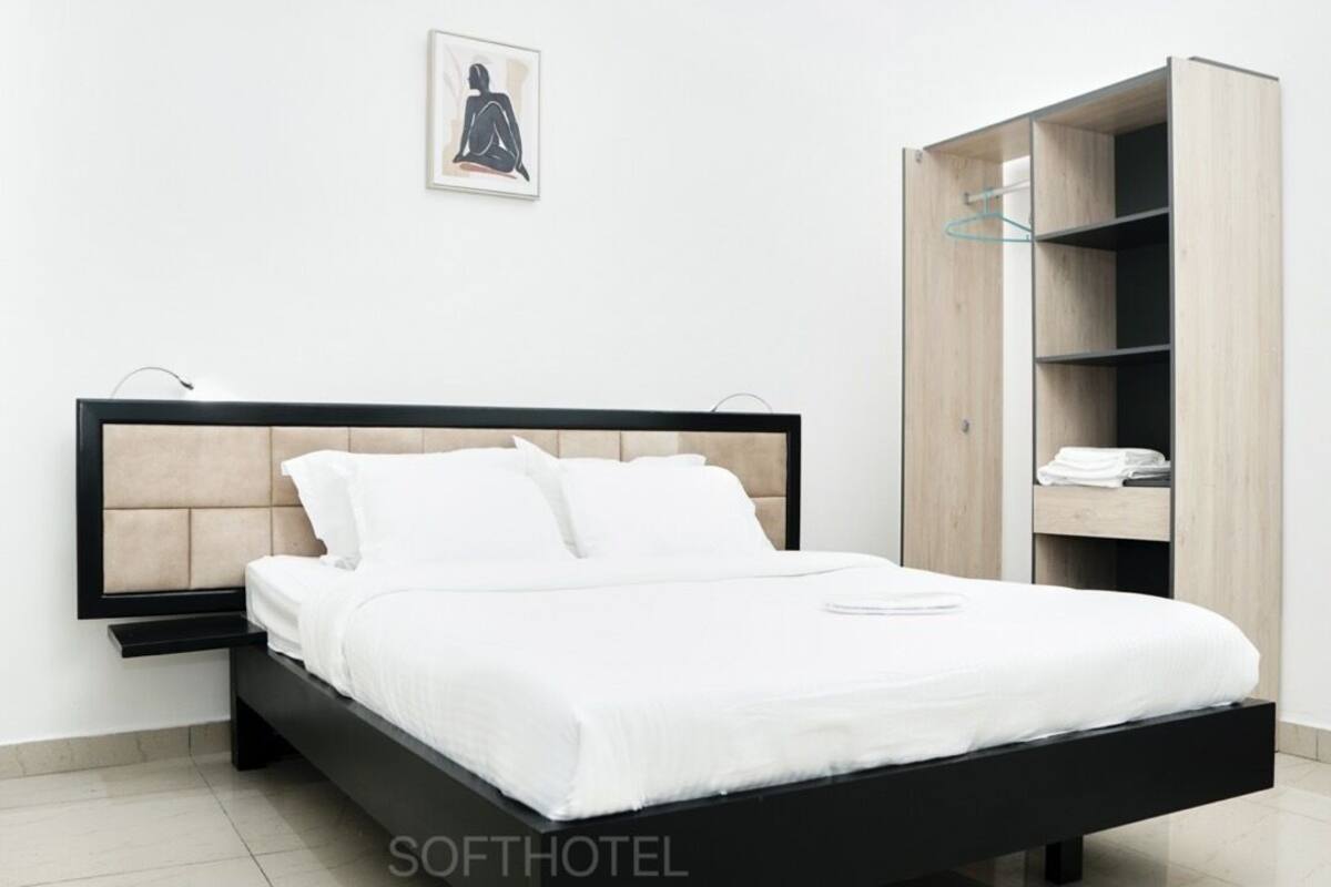 A modern bedroom with a bed, a wooden wardrobe, and a framed picture on the wall.