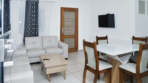 A modern living room with a sofa, coffee table, dining table, and chairs. - SOFT HOTEL (Douala)