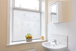Un bagno con finestra, lavandino e specchio.
