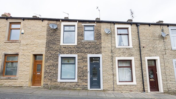 A row of terraced houses with individual front doors, windows, and satellite dishes.