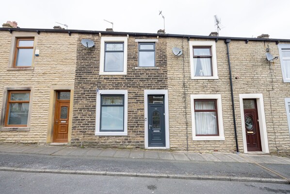 A row of terraced houses with distinct front doors, windows, and satellite dishes.