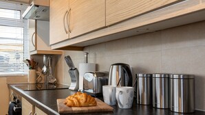 Uma cozinha com bancada de madeira, eletrodomésticos de aço inoxidável e um croissant em uma tábua de corte.