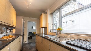 Une cuisine moderne avec des meubles en bois, un évier en acier inoxydable et une fenêtre équipée de stores.