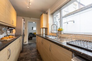 A modern kitchen with wooden cabinets, a stainless steel sink, and a window with blinds.