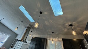 A modern kitchen with skylights, pendant lights, and dark cabinetry. - Miller Beach Family Getaway (Gary)