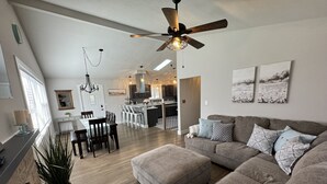 A spacious living area with a grey sofa, a dining table, and a kitchen in the background. - Miller Beach Family Getaway (Gary)
