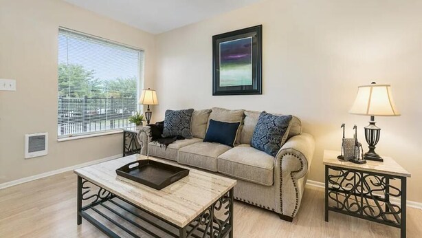 A living room with a beige sofa, a coffee table, a side table with a lamp, and a ceiling fan. - Lovely top floor corner apt in trendy SugarHouse (Salt Lake City)