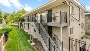 A multi-story apartment building with a brick facade, balconies, and a well-maintained lawn. - Lovely top floor corner apt in trendy SugarHouse (Salt Lake City)
