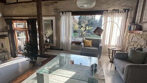 Een ruime woonkamer met een glazen salontafel, een bank en een kamerbreed tapijt met een patroon.