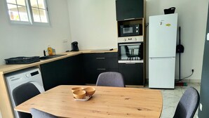 Una cocina compacta con una mesa de madera, dos sillas, un microondas, un refrigerador y un lavavajillas.