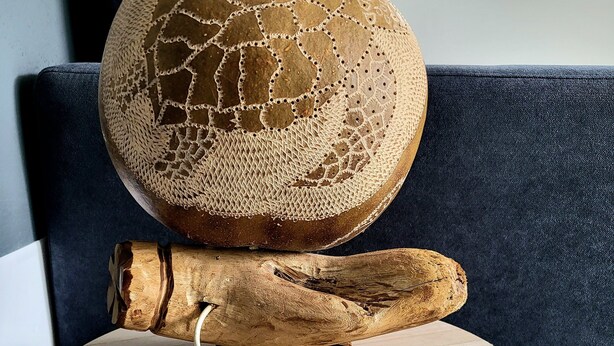 Una mesa redonda de madera con un diseño original, sobre un sofá azul oscuro.