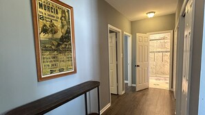 A hallway with a wooden bench, a framed poster on the wall, and a door leading to another room. - Unplug and unwind at your Leonardtown waterfront vacation home! (Leonardtown)