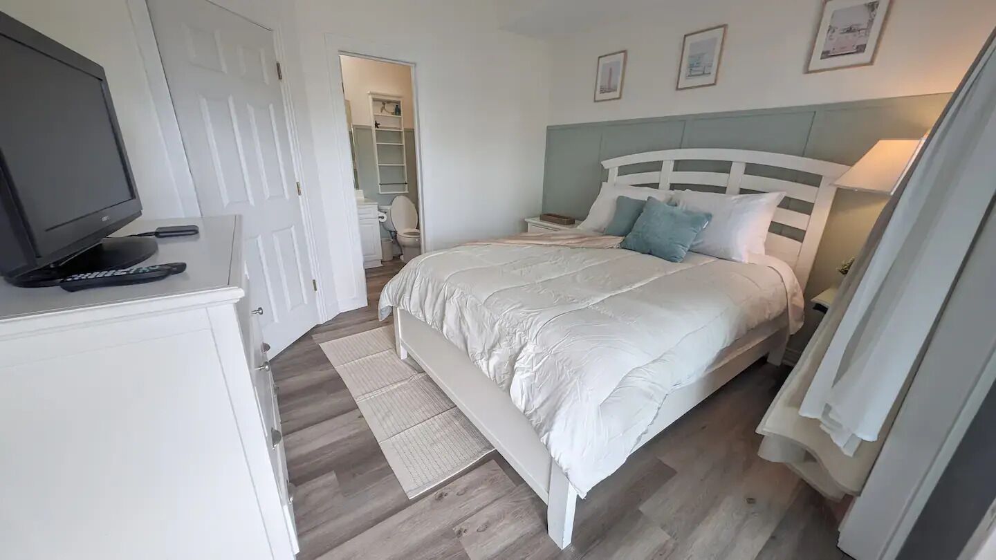 Une chambre à coucher comprenant un lit, une télévision, une table de chevet, une commode et une armoire.
