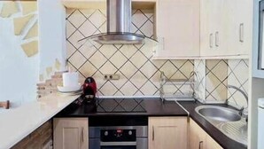 Een keuken met een kookplaat, oven, spoelbak en een betegelde spatwand.